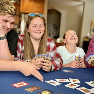 Three of the Camp kids playing Skip the Salad around the kitchen table